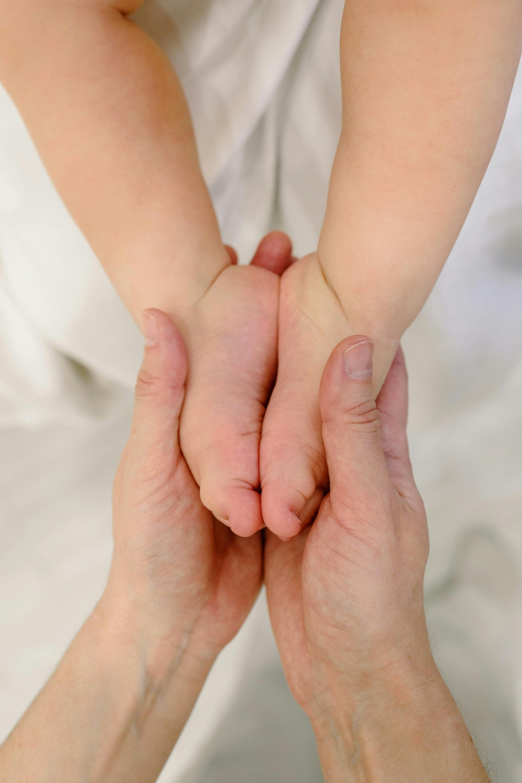Close-up of hands massaging baby feet, symbolizing tenderness and care.