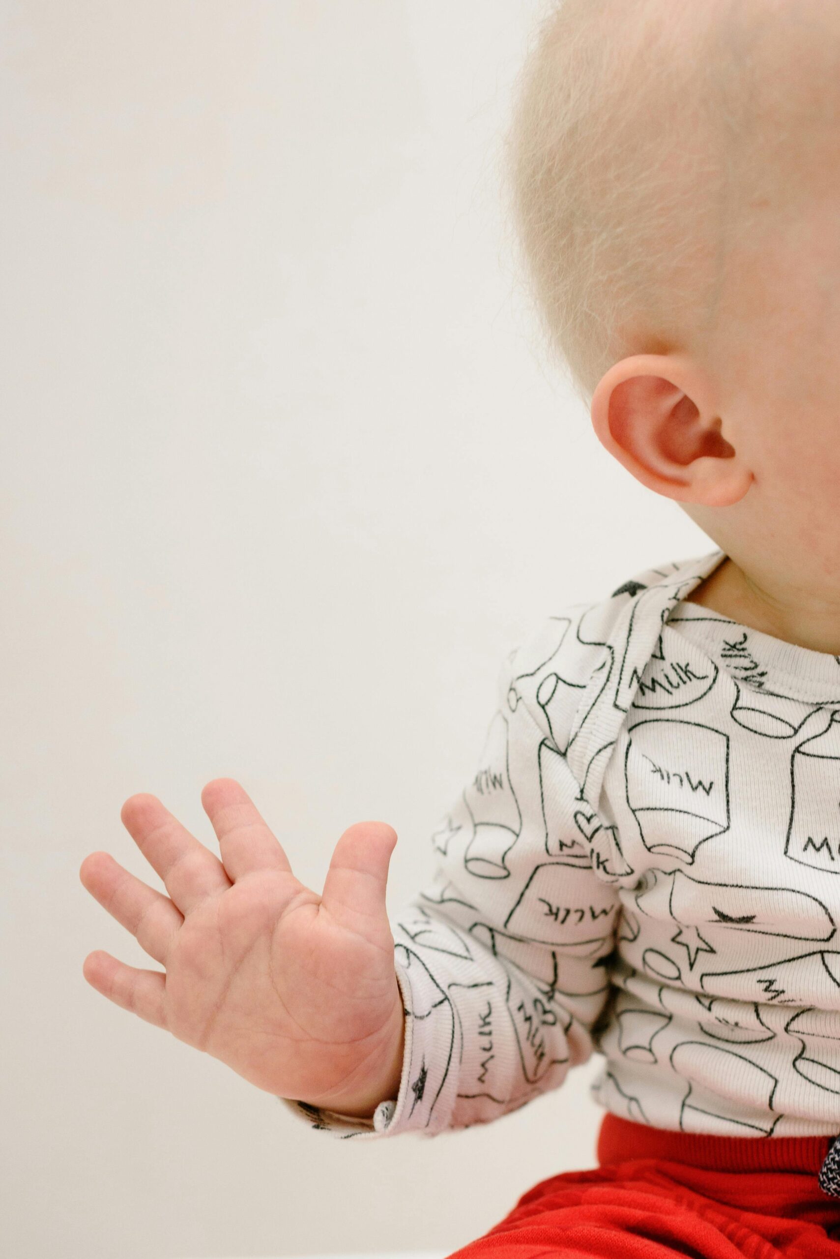 Close-up of a baby wearing a milk-themed outfit, hand extended. Perfect for baby-related content.